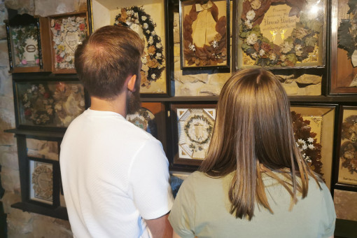 Eine Frau und ein Mann betrachten gemeinsam eine Bilderwand im Museum für Sepulkralkultur